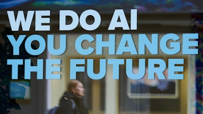 A woman is reflected in a window with a slogan about AI ahead of the World Economy Forum in Davos, Switzerland, Sunday, Jan. 19, 2025.