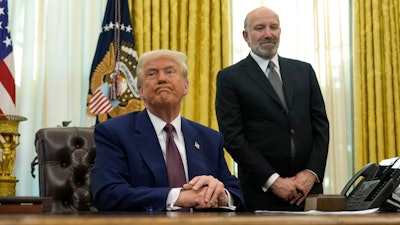 President Trump listens to a question from a reporter as Commerce Secretary nominee Howard Lutnick in the Oval Office, Feb. 13, 2025.