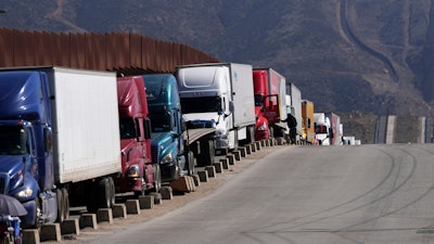 Trucks line up to cross the border into the United States as tariffs against Mexico go into effect, Tuesday, March 4, 2025, in Tijuana, Mexico.