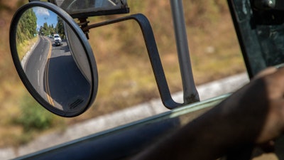 Trucks loaded with avocados reflected in a rear view mirror on the way to Uruapan, Mexico, Jan. 26, 2023.