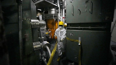 A worker in hazmat suit walks at the area under the Unit 5 reactor pressure vessel, which survived the earthquake-triggered tsunami in 2011, at the Fukushima Daiichi nuclear power plant, run by Tokyo Electric Power Company Holdings (TEPCO), in Futaba town, northeastern Japan, on Monday Feb. 20, 2025.