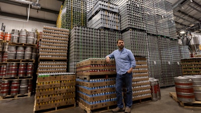 Jeff Ware, president of Resurgence Brewing Company, poses for a portrait near a stockpile of aluminum cans, which are sourced from Canada, Thursday, Feb. 27, 2025, in Buffalo, N.Y.