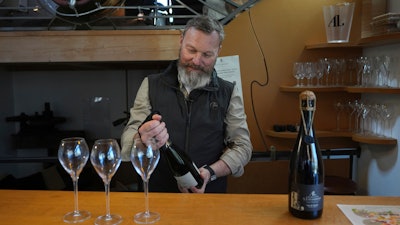 French wine grower David Levasseur opens a bottle of champagne in his wine making facility in Cuchery, eastern France, Monday, March 17, 2025.