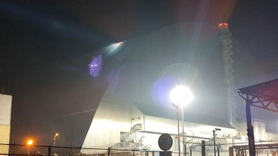In this photo provided by the Ukrainian Emergency Service, a searchlight illuminates the damages of a protective shell over the fourth reactor of the Chernobyl nuclear power plant following a drone strike, Friday, Feb. 14, 2025.