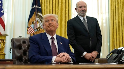 President Donald Trump listens to a question from a reporter as Commerce Secretary nominee Howard Lutnick watches after Trump signed an executive order in the Oval Office of the White House, Thursday, Feb. 13, 2025, in Washington.