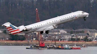 Salvage crews work on recovering wreckage near the site in the Potomac River of a mid-air collision between an American Airlines jet and a Black Hawk helicopter at Ronald Reagan Washington National Airport, Thursday, Feb. 6, 2025, in Arlington, Va.