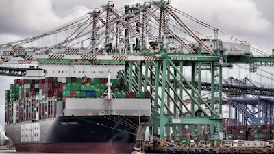 A sailboat passes a cargo ship unloading containers at the port of Los Angeles in San Pedro on Thursday, June 15, 2023.